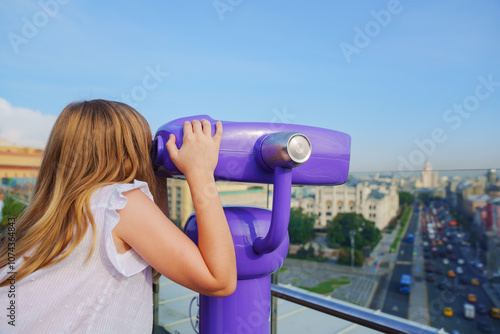 a teenage girl looks into the Binoscope from the observation deck at a height.  photo