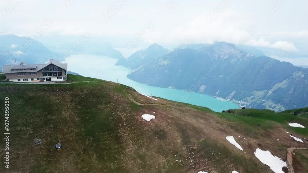 Aerial view of The Fronalpstock mountain peak with the chair lifts and revealing the green lake at the base of the mountain in Switzerland, in the Schwyzer Alps and the canton of Schwyz. Aerial view of The Fronalpstock mountain peak with the chair lifts and revealing the green lake at the base of the mountain in Switzerland, in the Schwyzer Alps and the canton of Schwyz.