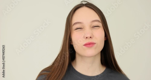 Young woman looks attentively and incredulously at camera with serious expression on face on white background photo