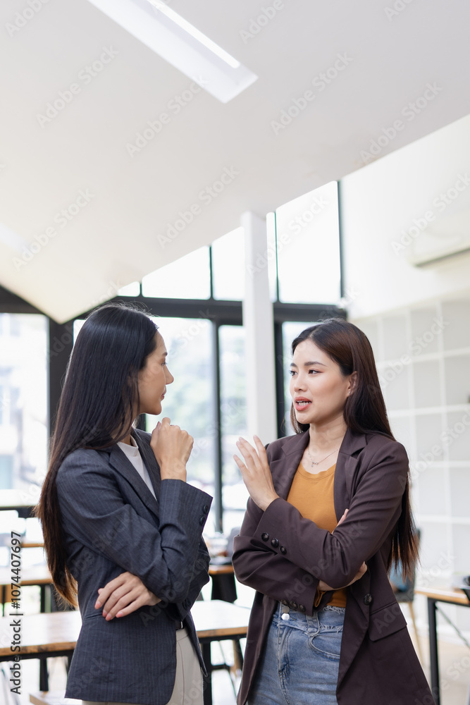 Two Asian business female talking to partner standing in office.
Two Asian business female talking to partner standing in office.