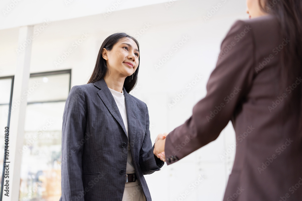 Two young Asian female making handshake inside at office workplace, partner, greeting, businesswomen handshake. Two young Asian female making handshake inside at office workplace, partner, greeting, businesswomen handshake.
