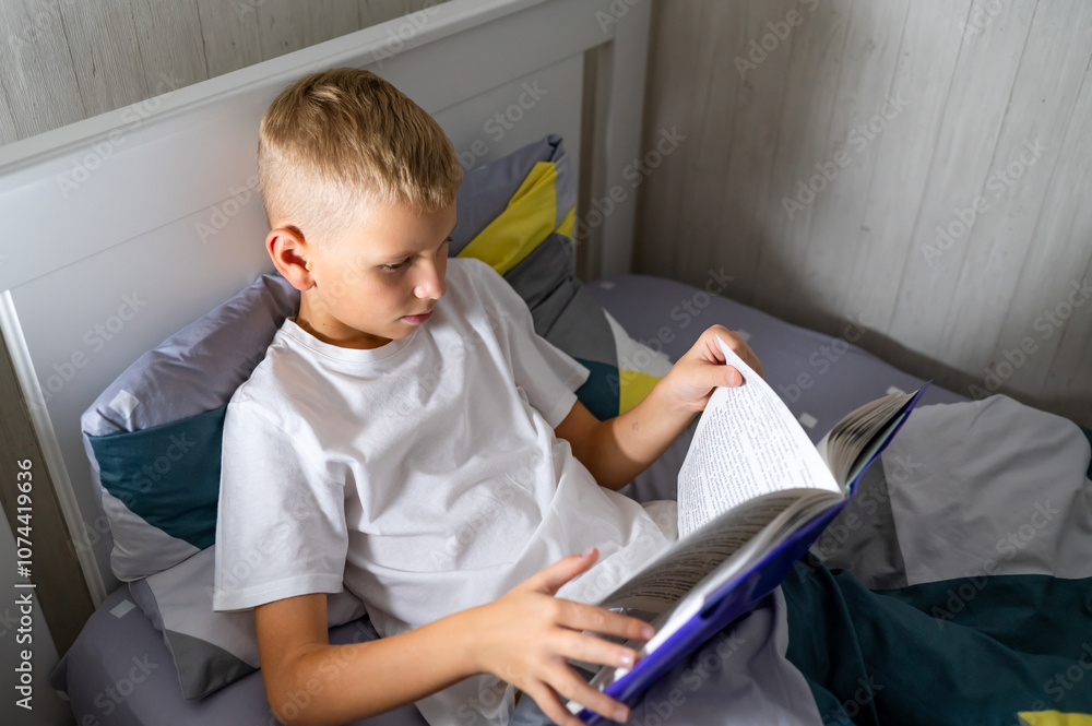 fair-haired teenage boy reading a book before bed fair-haired teenage boy reading a book before bed