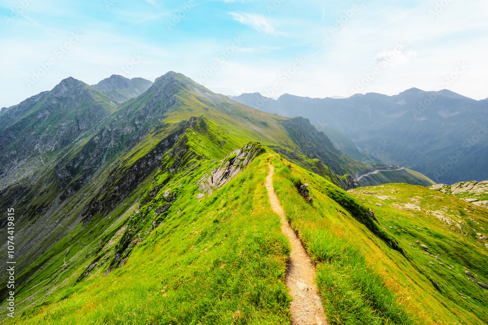 Fototapeta premium Hiking in Fagaras mountains on Iezerul Caprei peak over Transfagarasan serpentine road carpathian mountains. Mountains landscape