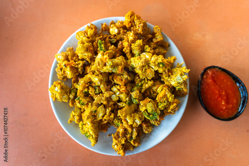 Top view of crispy and addictive cabbage pakoda (Cabbage fritters) with red tomato chatney, a popular tea time snack in india. They are made up of cabbage instead of traditionally used onions. photo