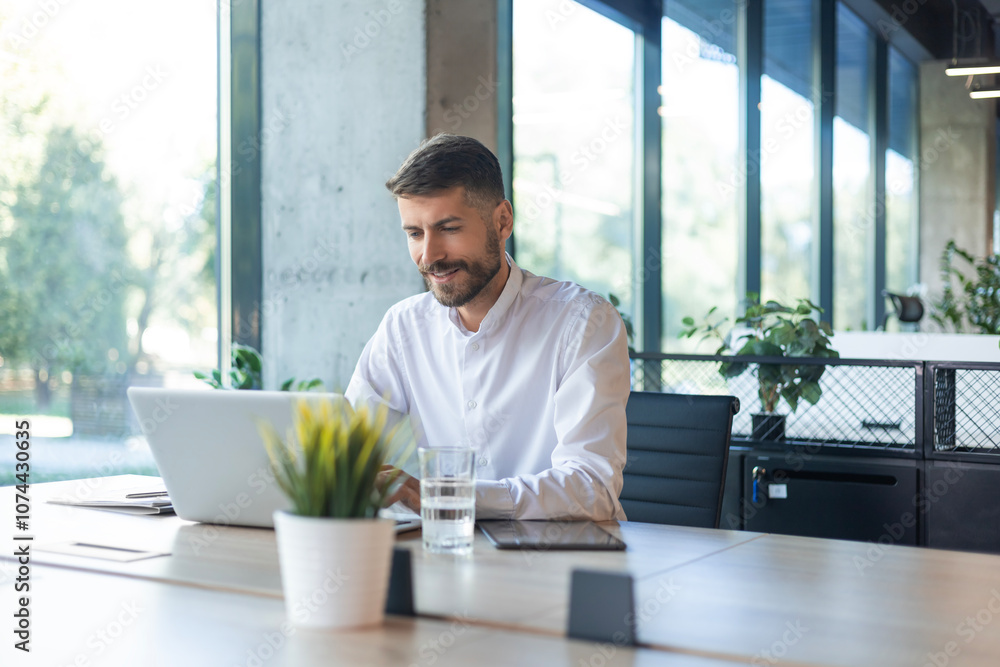 Young handsome businessman using laptop at his office desk Young handsome businessman using laptop at his office desk