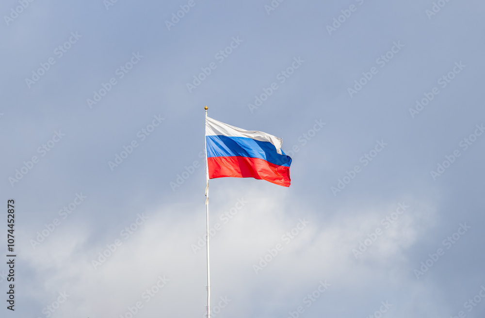 Russian tricolor flag waving in the wind against a blue sky. Russian tricolor flag waving in the wind against a blue sky.