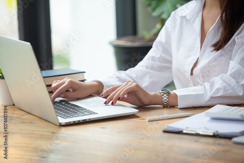 Closeup shot of business woman's hand using pen and writing in computer notebook business calculations or a female student using a computer The phone works for Exam preparation, presentations