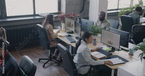 High angle view of busy coworking center with diverse group of people employees working at desks. Office workers and successful business concept.