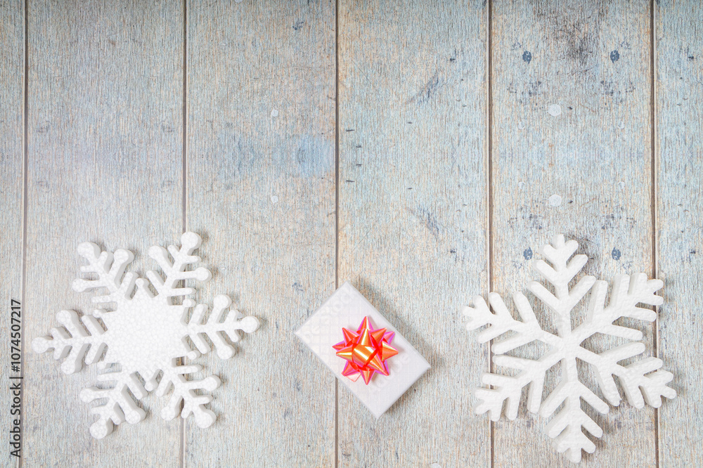 White decorative snowflakes and giftbox on white wooden background, copy space White decorative snowflakes and giftbox on white wooden background, copy space