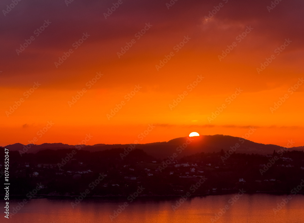 Striking sunset over mountains with ocean in the foreground Striking sunset over mountains with ocean in the foreground