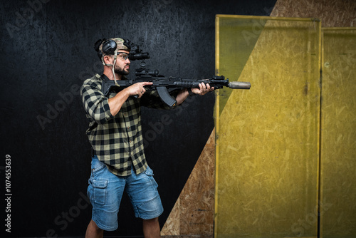 A private military in civilian clothes practices tactical shooting with night vision and a ak rifle with a suppressor at a indoor shooting range. photo