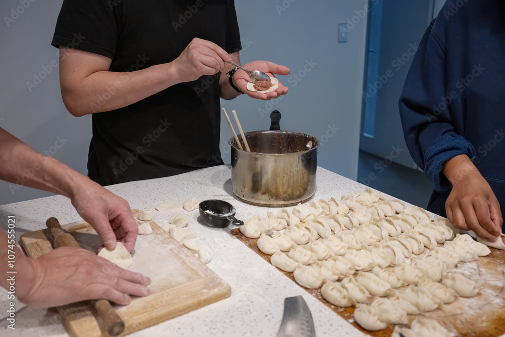 Family making wrappers and dumplings at home. Home cooking.
