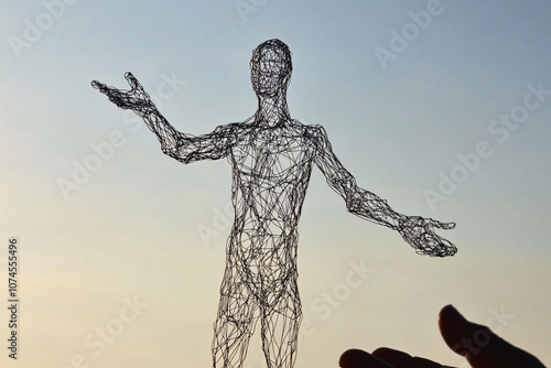 a wire sculpture of a human figure with outstretched arms standing against a bright sky blending artistry and abstraction 