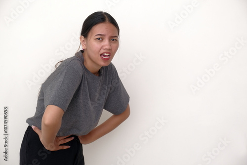 Side view: A young woman bent over, holding her stomach with a pained expression photo