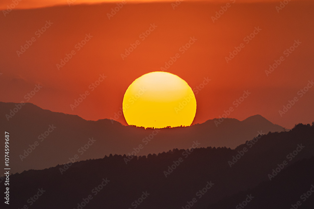 Obraz premium 夕焼けの中、山に沈む太陽