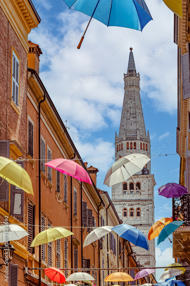 Colorful umbrellas create a vibrant canopy over a charming street in a scenic town of the Modena, Italy,