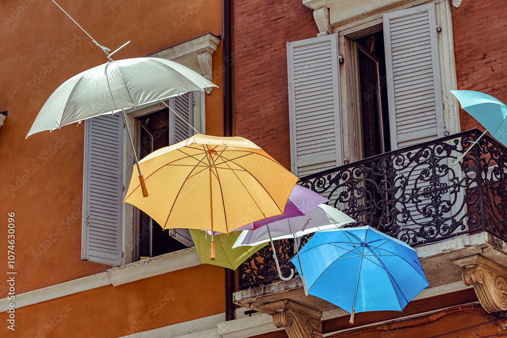 Colorful umbrellas create a vibrant canopy over a charming street in a scenic town of the Modena, Italy,