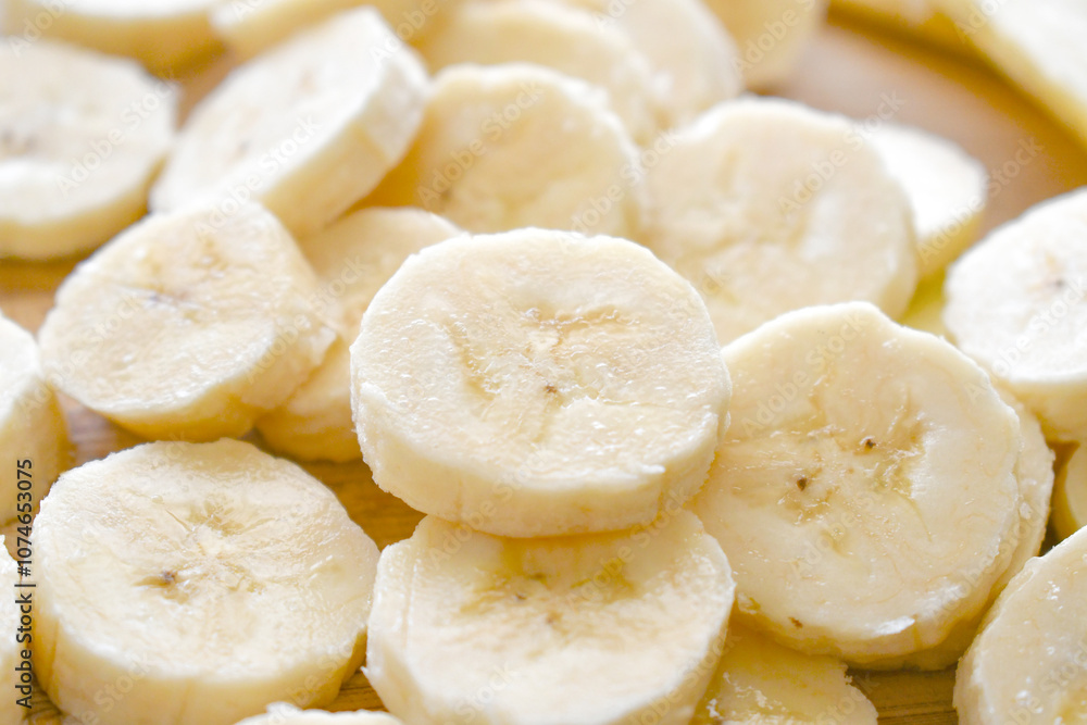 Banana slices on a bamboo cutting board.
