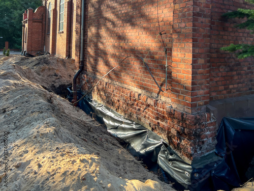 Securing the foundations of existing, old buildings against moisture. Excavation, cleaning, reinforcement of joints, insulation and backfilling with earth