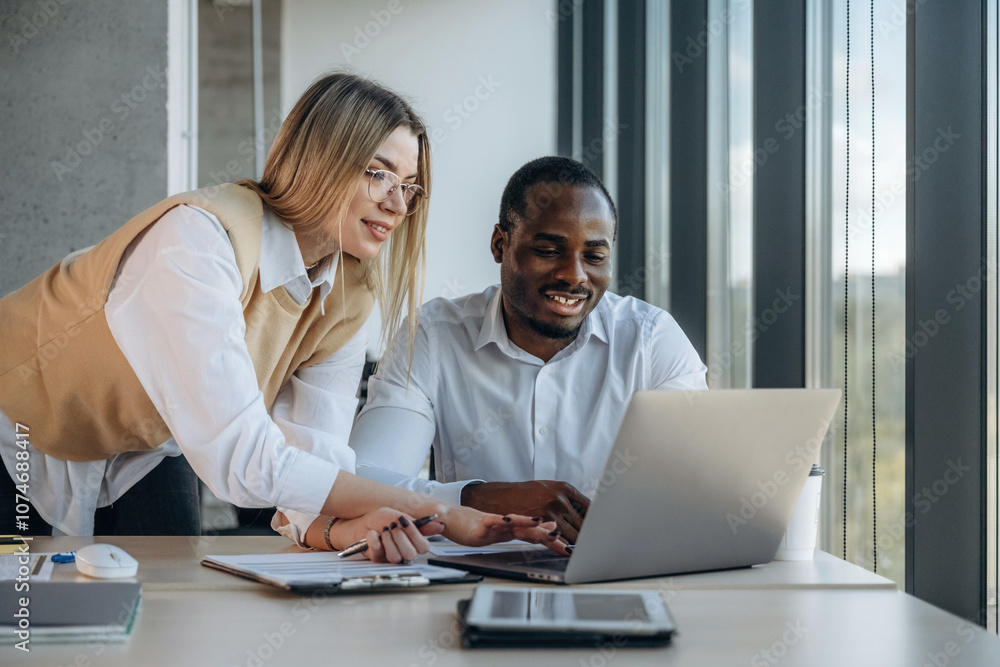 By the laptop. Two business people are working together in the office By the laptop. Two business people are working together in the office
