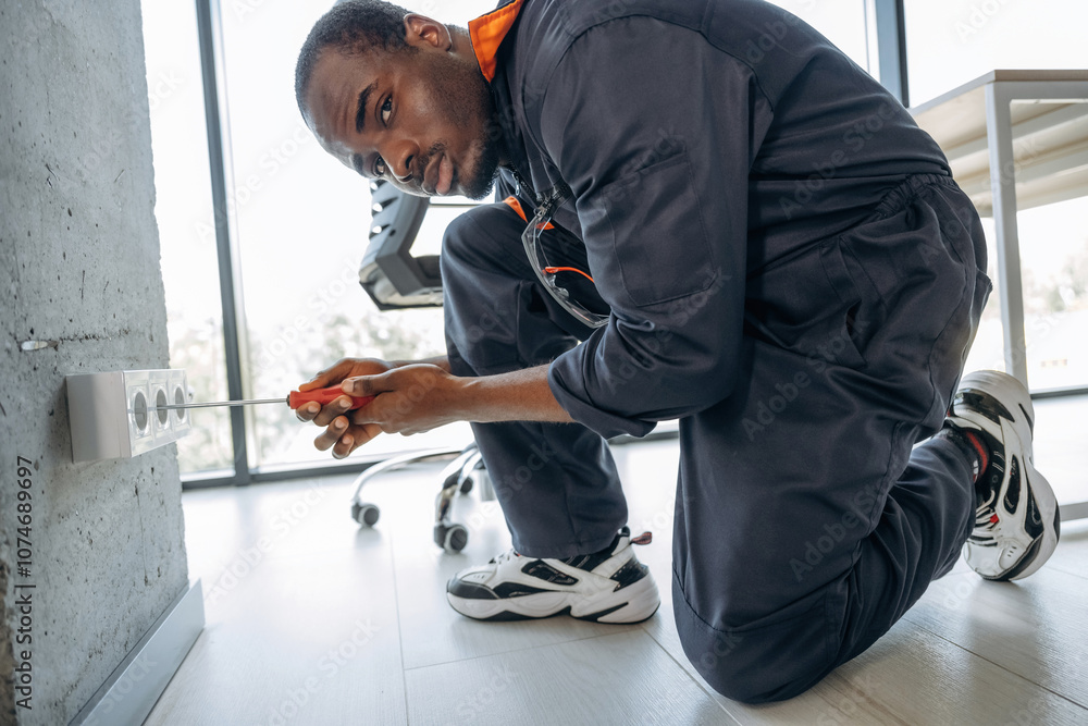 Fototapeta premium Process of installation of the socket. Repairman is indoors in the modern office