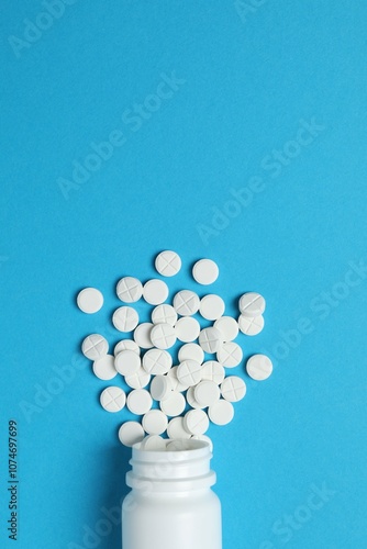 Various medicines and health pills poured from a medical white bottle, healthcare and medical top view on a colorful blue background. 