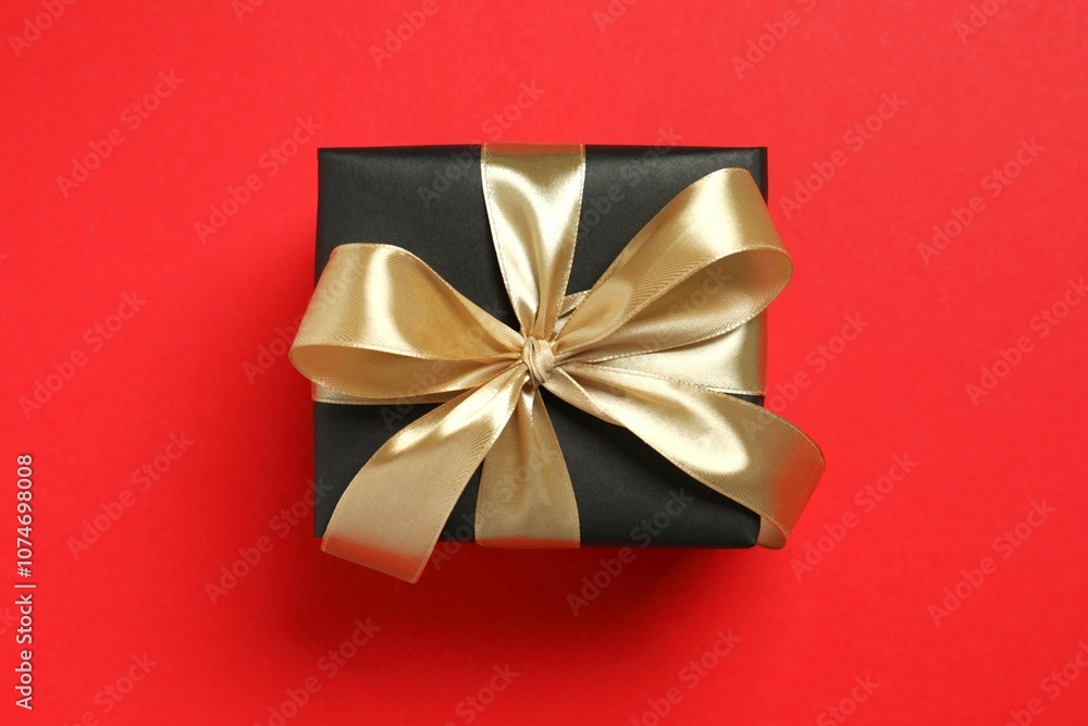 Beautiful gift box tied with golden bow on color background Beautiful gift box tied with golden bow on color background