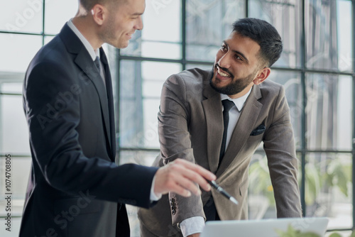 two professional businessmen discussing and using desktop computer in office