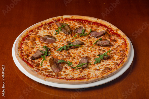 Italian pizza with roast beef and cheese on a plate on a wooden background