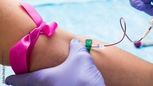 Obraz na plátně Drawing blood from a patient's arm using a syringe with a butterfly needle and a pink tourniquet in hospital