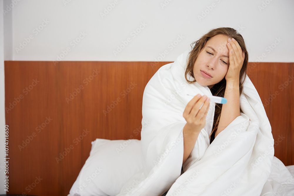 young woman having a cold or headache and reading temperature on thermometer young woman having a cold or headache and reading temperature on thermometer