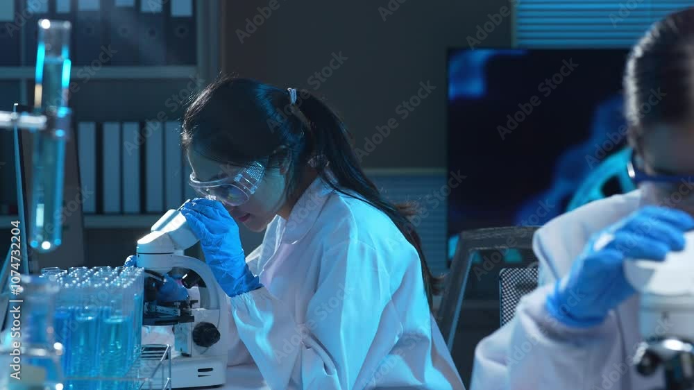 Female scientist using microscope analyzing sample in modern laboratory