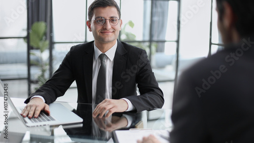 Thoughtful diverse colleagues sit at desk in office talk discuss business ideas at briefing together,