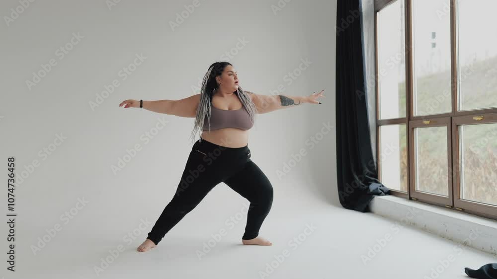 Happy body positive fat woman with dreadlocks doing yoga in the gym. Concept of natural diverse beauty and sport. Stout over weight female stretching isolated. Relaxation and tranquilty concept. Happy body positive fat woman with dreadlocks doing yoga in the gym. Concept of natural diverse beauty and sport. Stout over weight female stretching isolated. Relaxation and tranquilty concept.