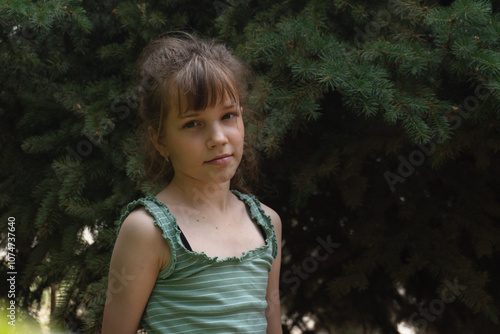 Portrait of a teenage girl 10 or 11 years old against a background of spruce photo