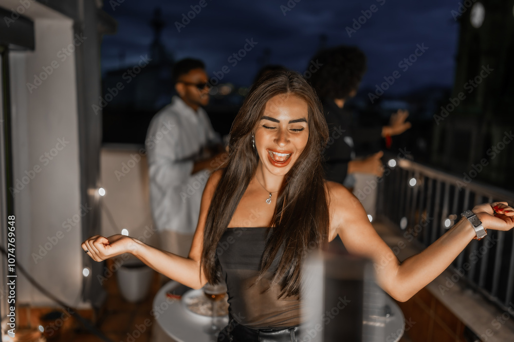 Fototapeta premium Happy woman dancing during night party on a city rooftop