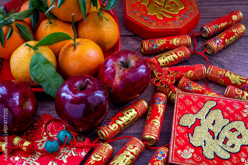 Close up of a plate of tangerines and red apples. Lunar New Year decorations and red packets with good fortune, health, wealth words on them. A Chinese New Year background, concept.