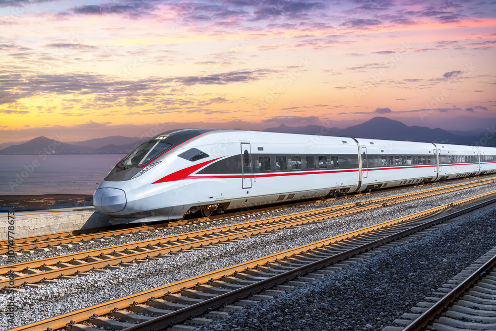 Fototapeta premium High-Speed Train Travel Along Scenic Coastline at Sunset