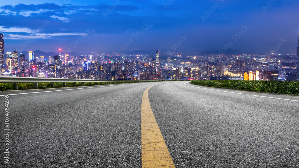 Obraz premium Scenic Cityscape at Night with a Curved Road Leading into the Skyline