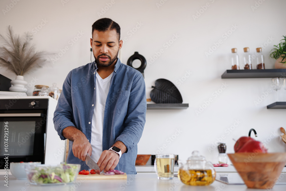 African american man cutting vegetables while cooking salad near teapot in kitchen African american man cutting vegetables while cooking salad near teapot in kitchen