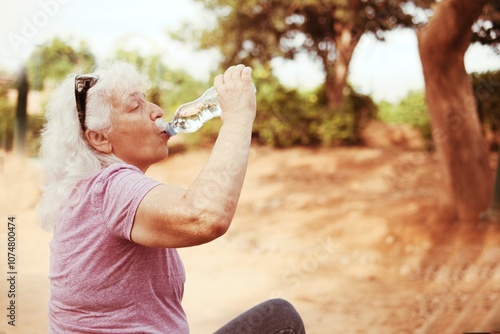 Thirst in the desert. An elderly lady greedily drinks water from a bottle. photo