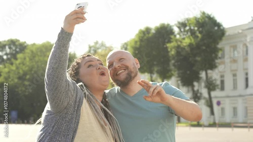 Portrait of happy overweight couple smiling and making selfie outdoor. Cheerful fat man and woman enjoy time spending together. Bset friends, body positive concept. Fat people love themselves photo