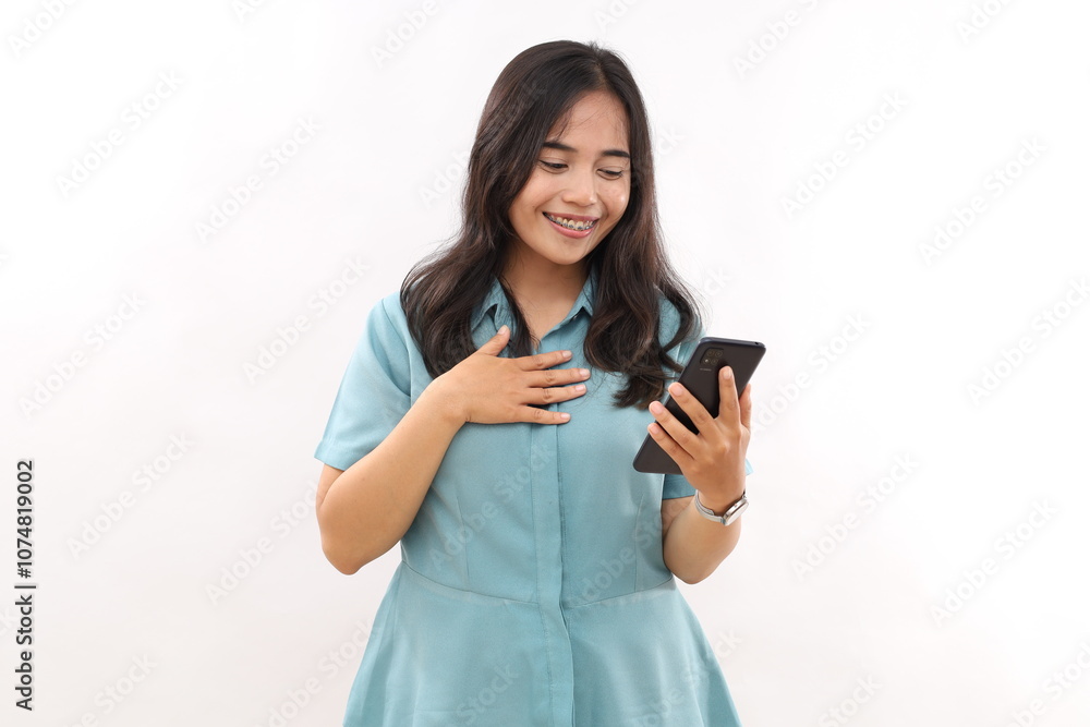 Portrait of pleased asian woman keeps palm on chest, being touched by heartwarming words, holds modern electronic device, receives good message, wears dressed casual shirt Portrait of pleased asian woman keeps palm on chest, being touched by heartwarming words, holds modern electronic device, receives good message, wears dressed casual shirt