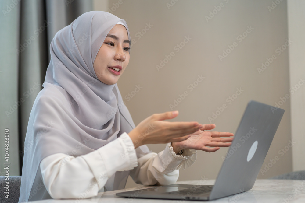 Muslim woman in hijab working on laptop sitting at desk in cozy home office, study on her task, freelance work, online education, remote work from home, modern muslim female business professional Muslim woman in hijab working on laptop sitting at desk in cozy home office, study on her task, freelance work, online education, remote work from home, modern muslim female business professional