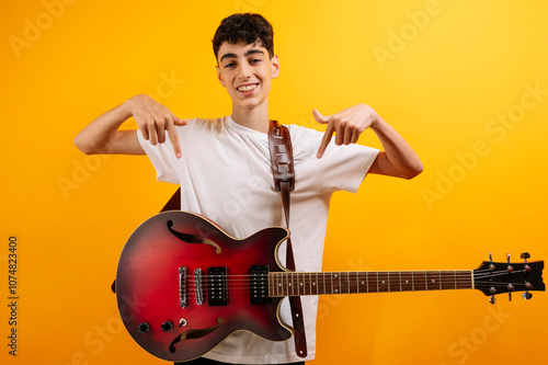 Teenager points to his red electric guitar.