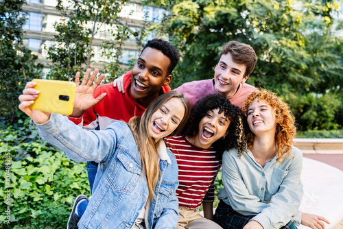 Konstfotografi Young diverse group of young people having fun taking selfie portrait sitting together outdoors while enjoying free time at city street