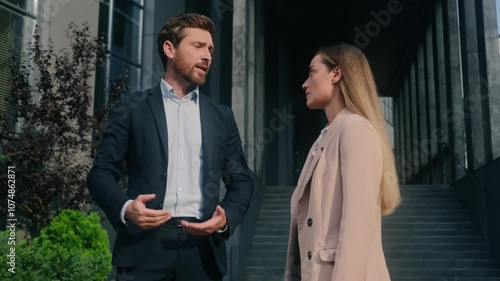 Two angry mad aggressive negative talking business people partners Caucasian businessman male man guy businesswoman woman female girl entrepreneurs conflict quarrel arguing scream in city work problem