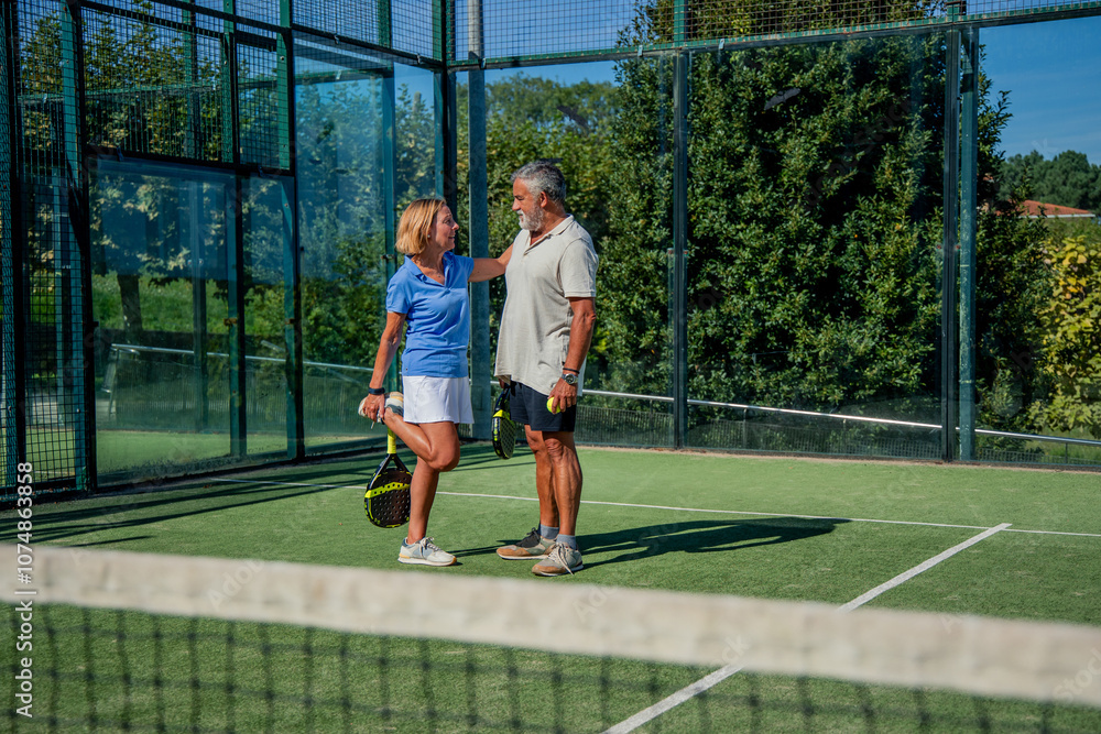 Senior elderly padel couple player stretching on court before match Senior elderly padel couple player stretching on court before match