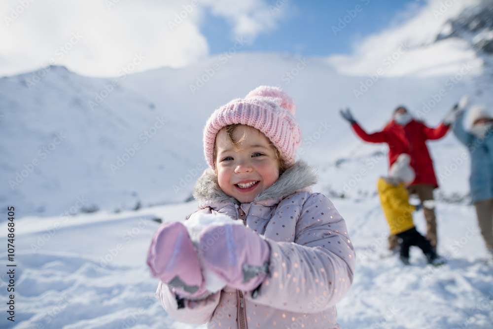 Portrait of small girl enjoying winter holiday in the mountains with family, playing in snow, having snowball fight. Portrait of small girl enjoying winter holiday in the mountains with family, playing in snow, having snowball fight.