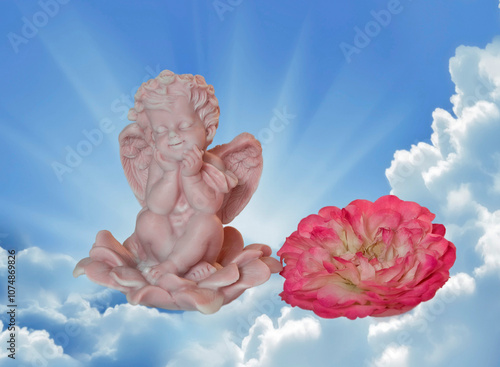 A figurine of a pink angel with a large rose flower against the background of a blue shining sky.